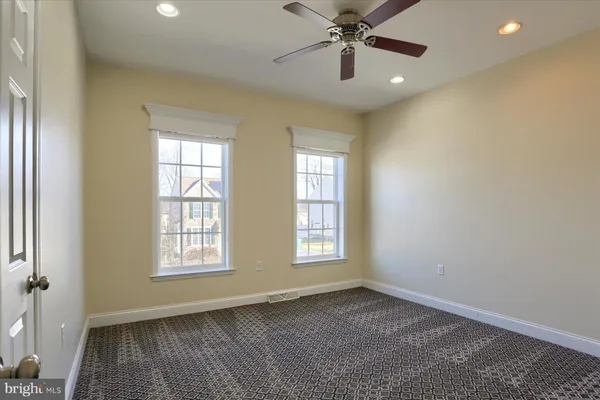 an empty room with windows and fan