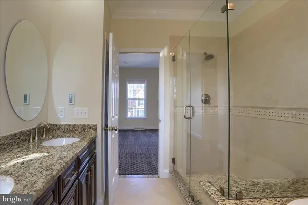 a bathroom with a granite countertop sink a mirror and shower