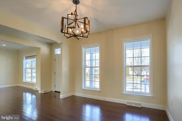 a view of a bedroom with wooden floor chandelier and windows