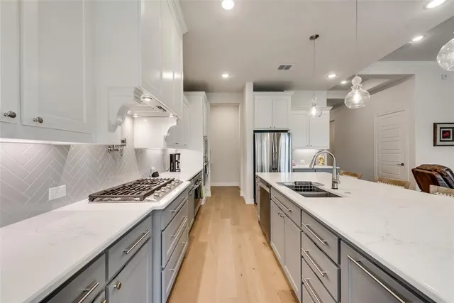 a kitchen with stainless steel appliances a sink a stove a refrigerator and chairs
