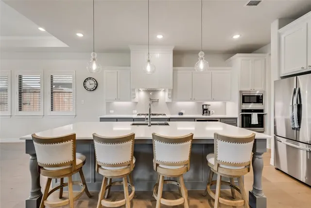 a kitchen with a dining table chairs stainless steel appliances and cabinets