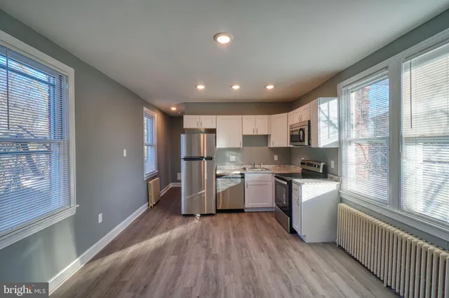 a kitchen with refrigerator and wooden floor