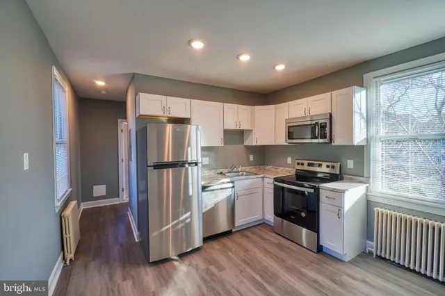 a kitchen with stainless steel appliances granite countertop a refrigerator a stove a sink dishwasher a oven with white cabinets and wooden floor