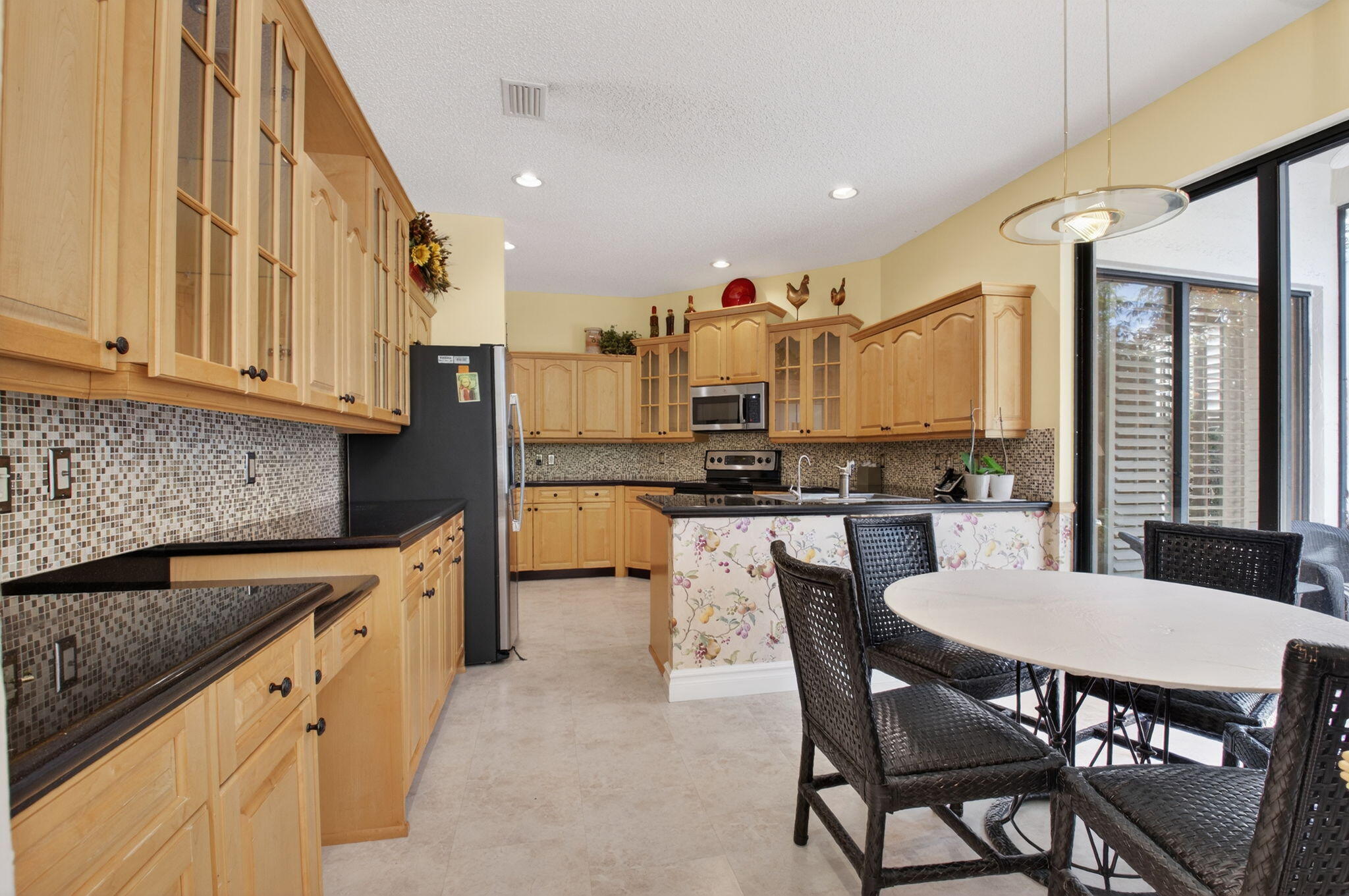 6395 Northwest 24th Avenue Boca Raton, FL 33496 - Photo 17 of 88 a kitchen with stainless steel appliances kitchen island granite countertop a table chairs sink and cabinets