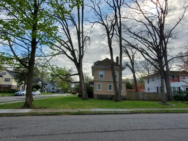 a view of a house with a yard and large trees