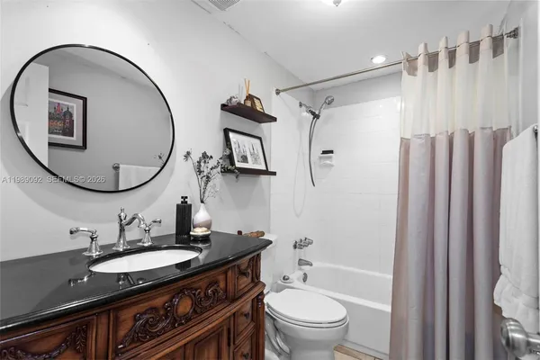 a bathroom with a granite countertop sink mirror toilet and shower