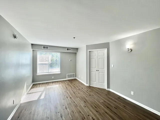 an empty room with wooden floor and windows
