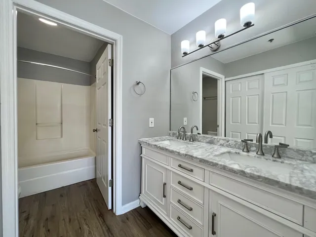 a bathroom with a granite countertop sink a mirror and a bathtub