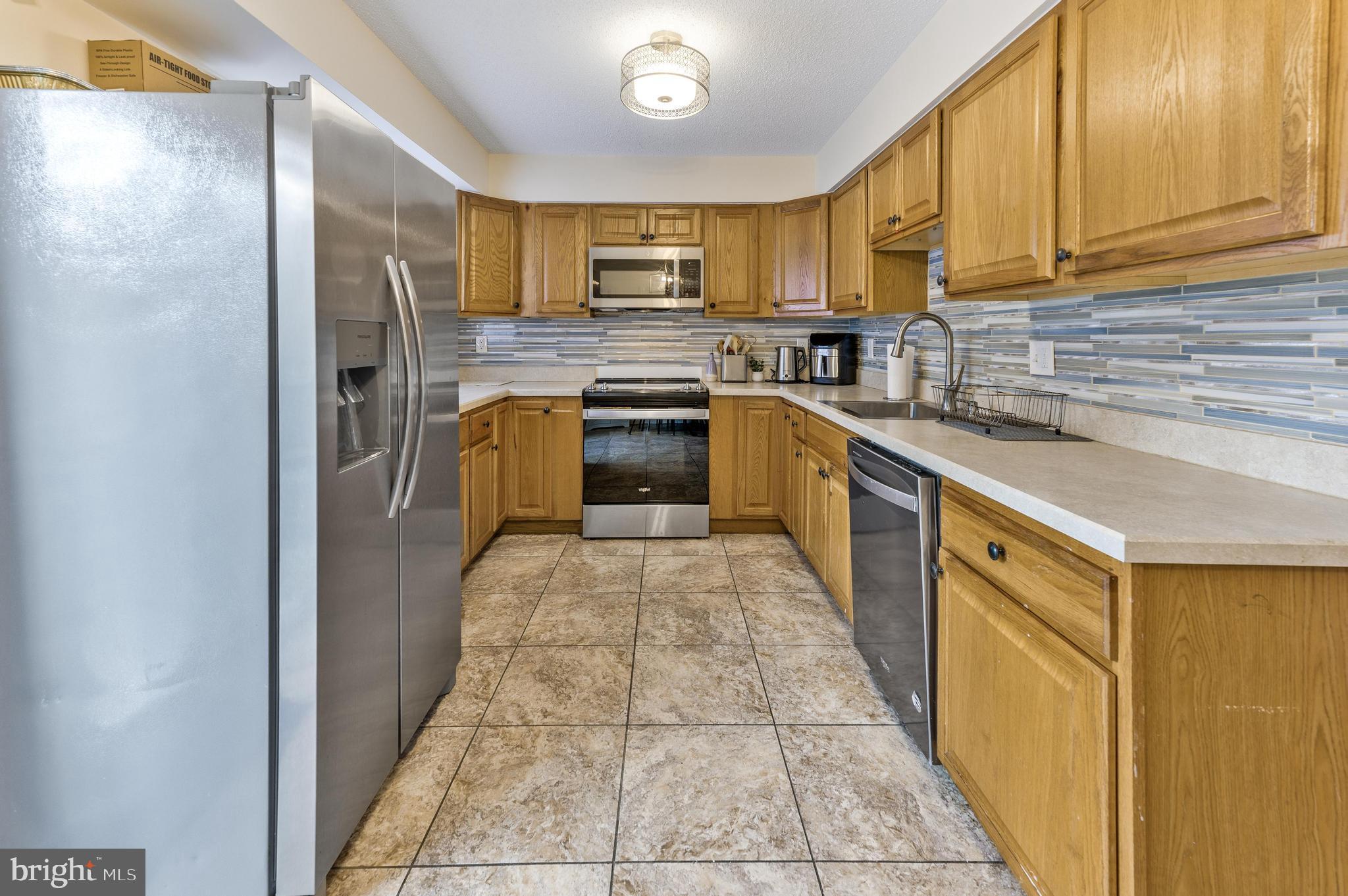 56 Dover Drive Lindenwold, NJ 08021 - Photo 9 of 20 a kitchen with stainless steel appliances granite countertop a refrigerator a sink dishwasher a stove with wooden cabinets and floor