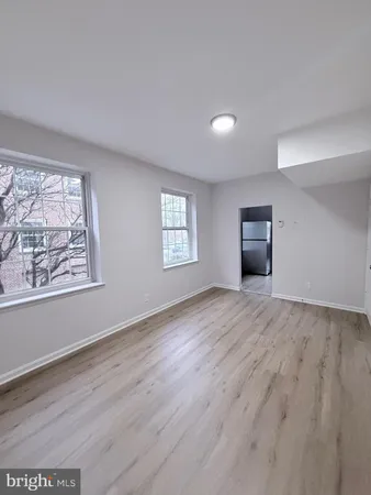 a view of an empty room with a window and wooden floor