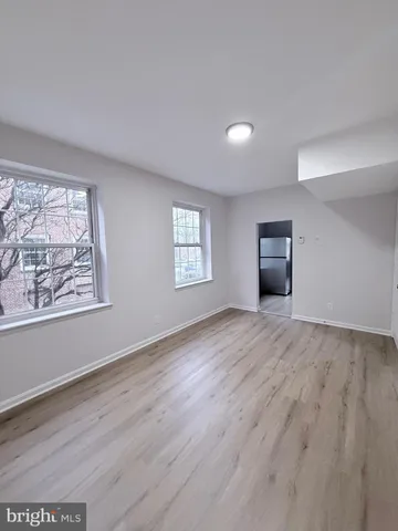 a view of an empty room with a window and wooden floor