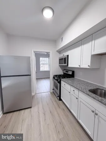 a kitchen with granite countertop a refrigerator stove top oven and sink