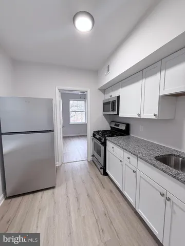 a kitchen with granite countertop a refrigerator stove top oven and sink
