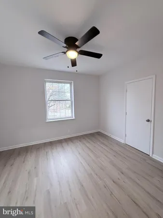 an empty room with wooden floor a ceiling fan and windows