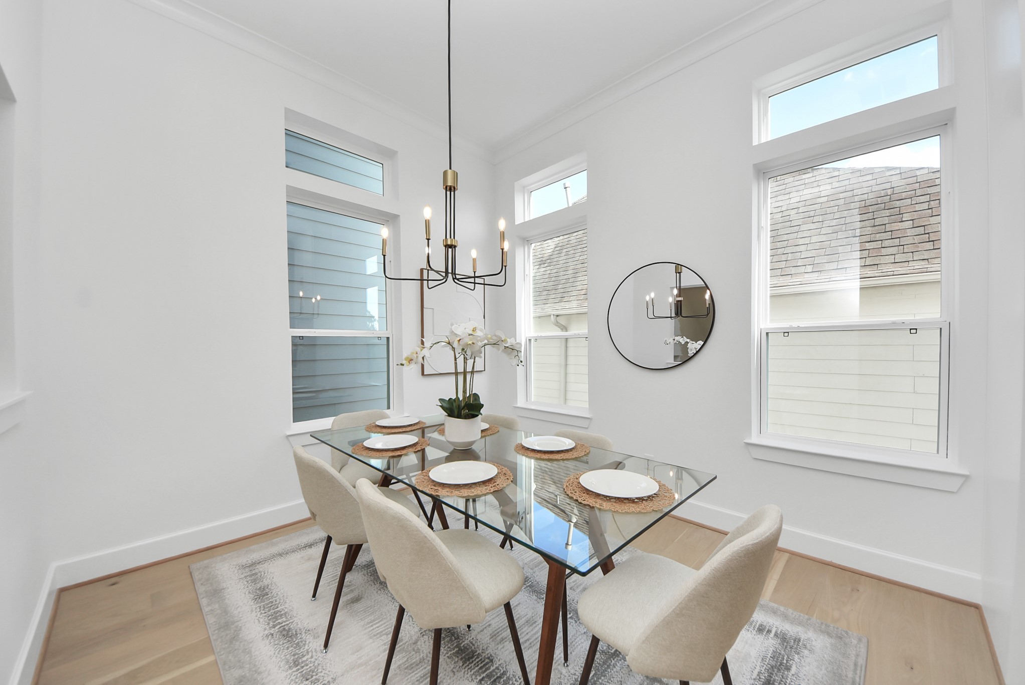 925 Fisher Street, Unit B Houston, TX 77018 - Photo 19 of 47 Step into this bright dining space with high ceilings and large windows, where modern decor complements a glass-top table with six upholstered chairs. A contemporary chandelier and decorative mirror add elegance, making this area both inviting and sophisticated.