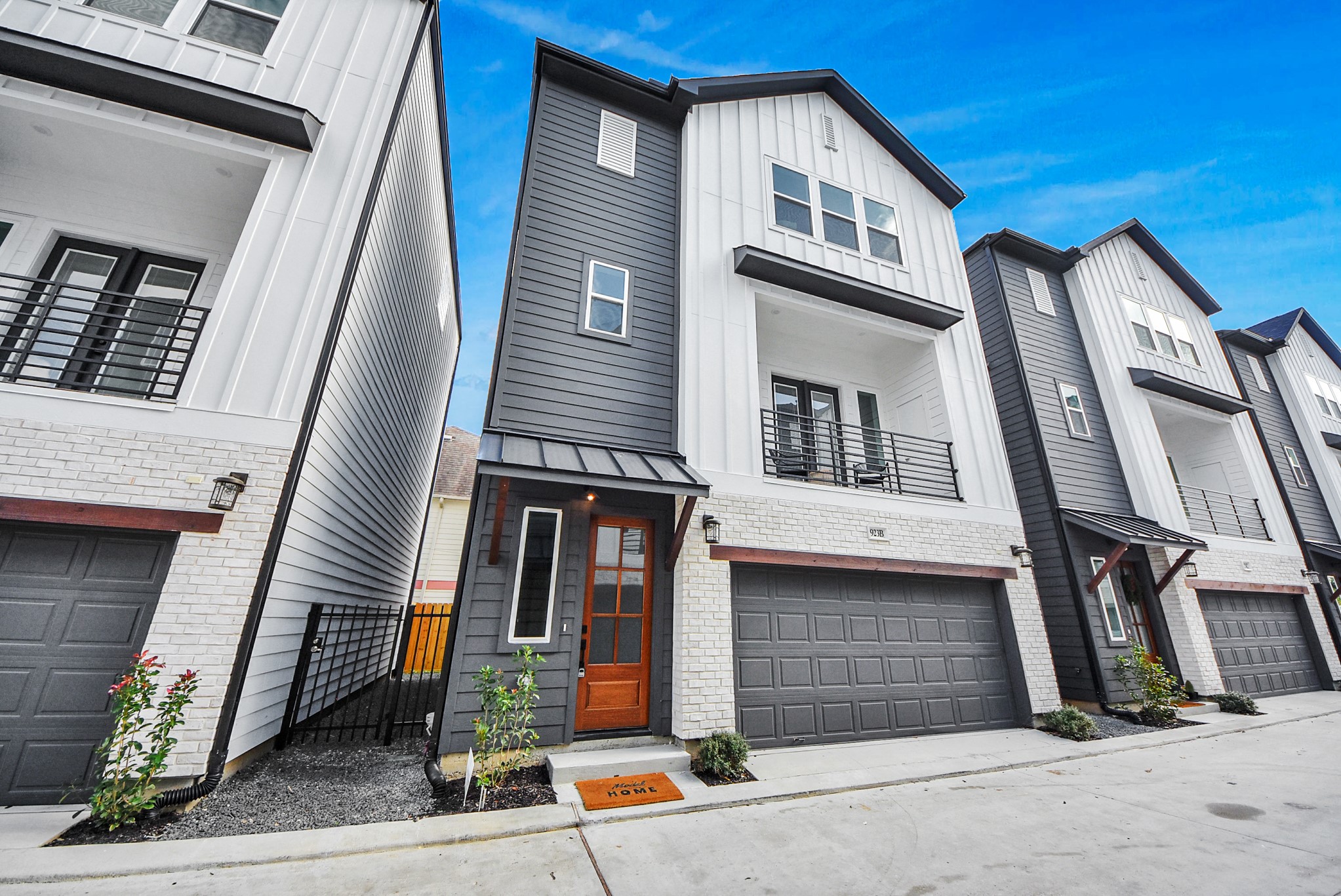 925 Fisher Street, Unit B Houston, TX 77018 - Photo 43 of 47 This modern townhouse welcomes you with a sleek exterior in white and dark gray siding, a warm wooden door, a two-car garage, and a balcony. A small landscaped area enhances curb appeal, making it perfect for contemporary living.