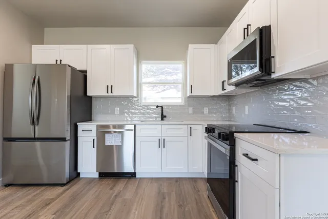 a kitchen with white cabinets white stainless steel appliances and wooden floors