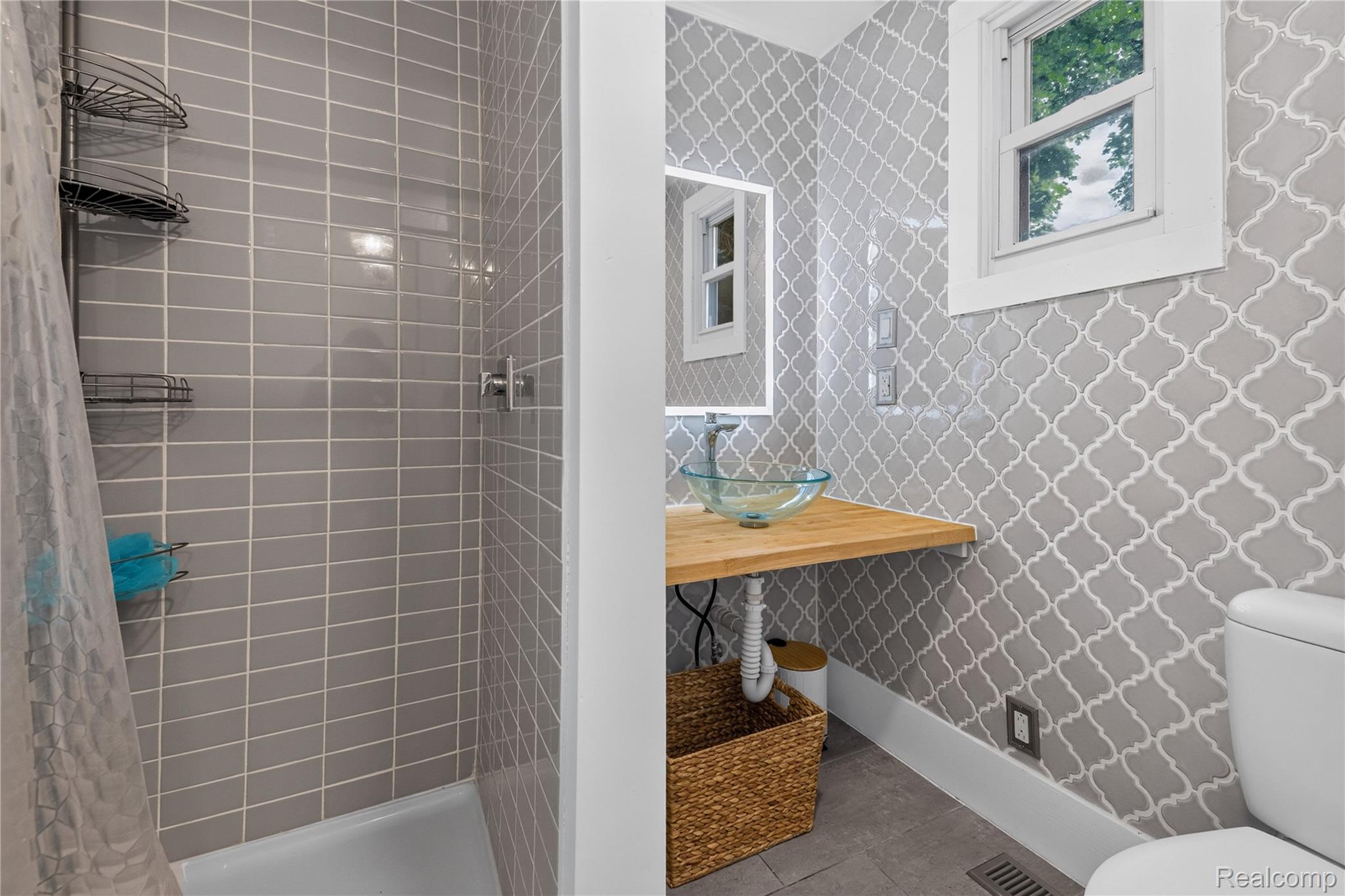 4860 Blue Bush Road Monroe, MI 48162 - Photo 30 of 59 Bathroom featuring a patterned wall tile accent, a clear glass vessel sink, and a wood-finish floating vanity