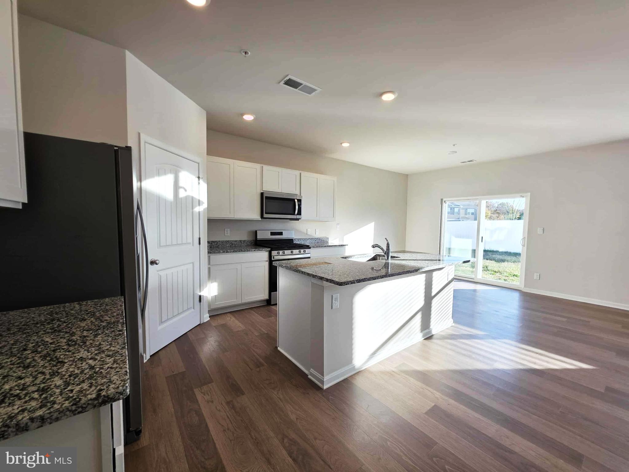 374 Robbins Farm Road Cambridge, MD 21613 - Photo 16 of 48 a large kitchen with a center island wooden floor stainless steel appliances and windows