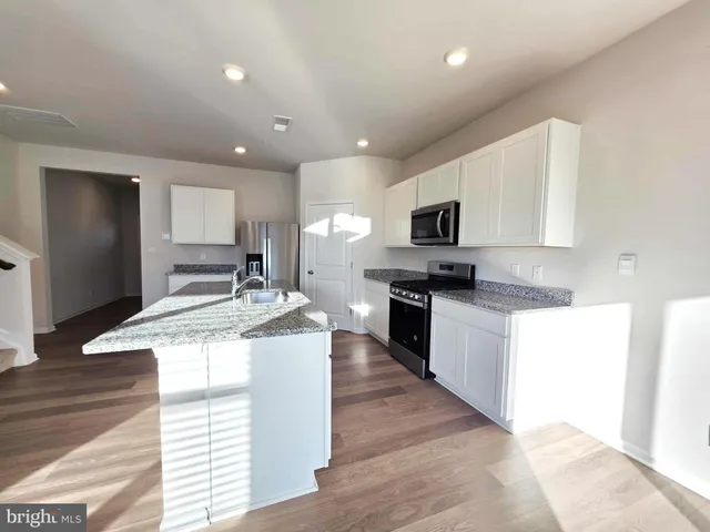 a kitchen with granite countertop kitchen island a sink stove and cabinets