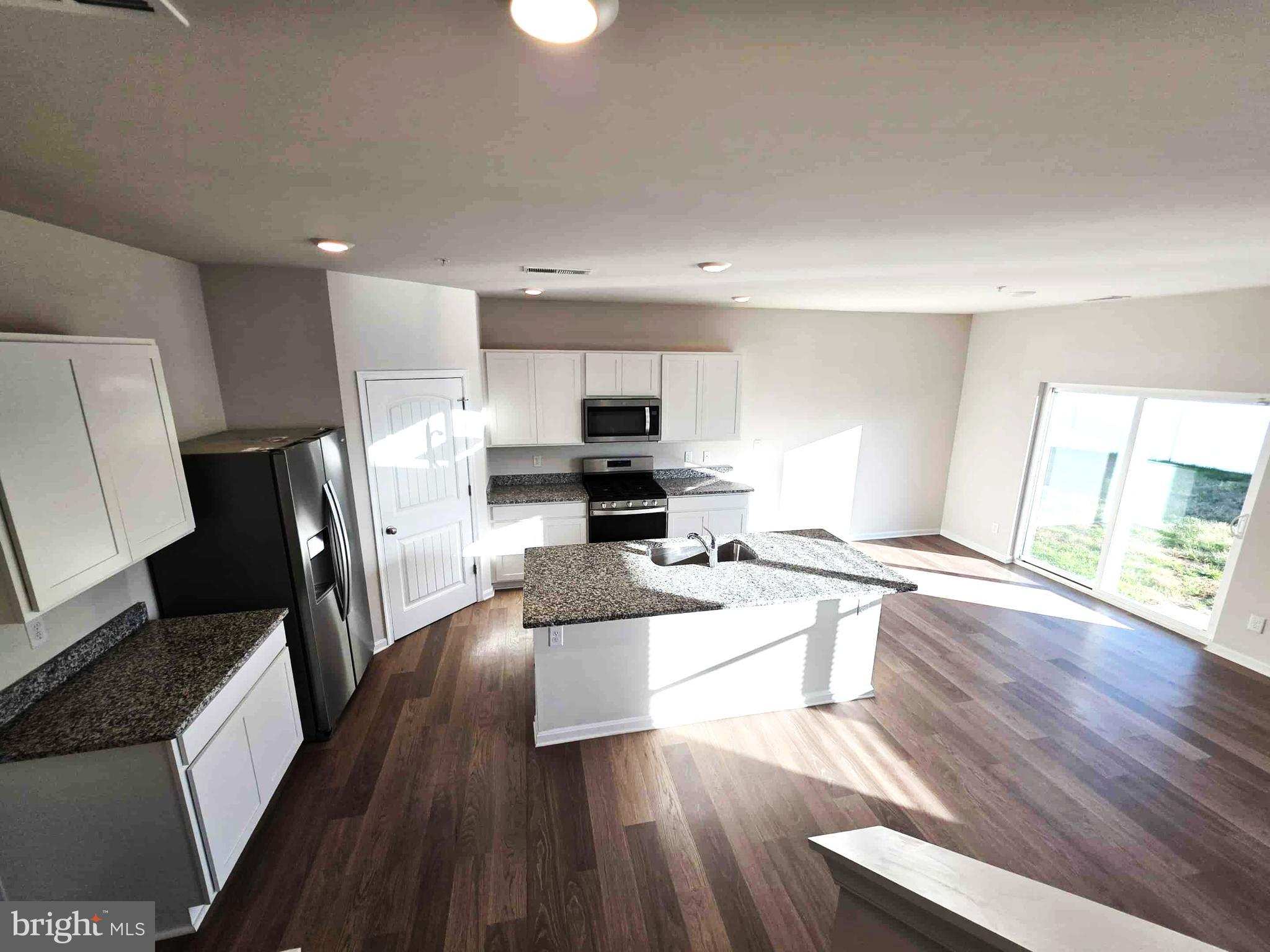 374 Robbins Farm Road Cambridge, MD 21613 - Photo 25 of 48 a kitchen with granite countertop a refrigerator a stove top oven a sink dishwasher and white cabinets with wooden floor