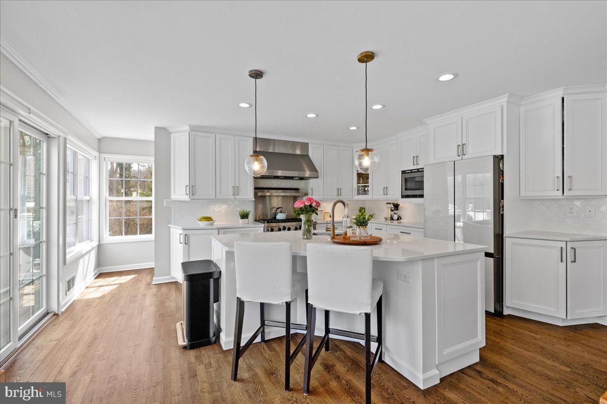 67 Randall Road Princeton, NJ 08540 - Photo 14 of 47 a kitchen with stainless steel appliances kitchen island granite countertop a refrigerator a stove a microwave oven a dining table and chairs with wooden floor