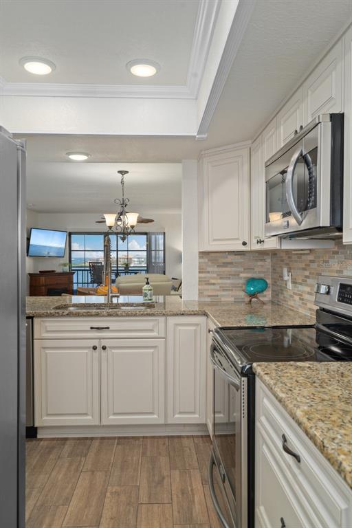 8211 Brent Street, Unit 847 Port Richey, FL 34668 - Photo 14 of 29 a kitchen with stainless steel appliances granite countertop a sink and dishwasher a stove top oven with wooden floor