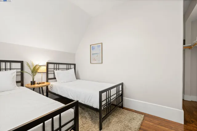 a bedroom with two beds and wooden floor