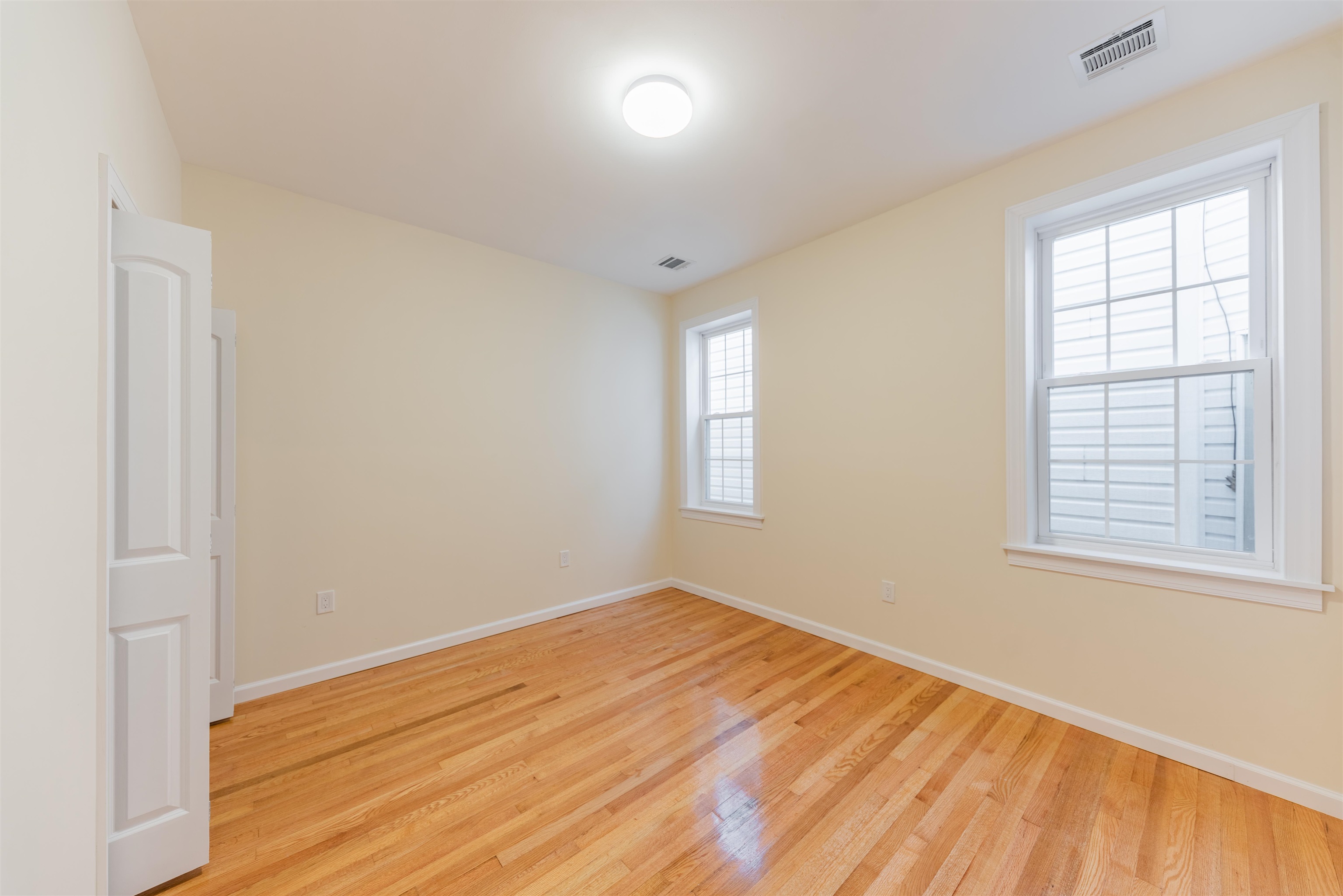 67 70th Street, Unit 2 Guttenberg, NJ 07093 - Photo 5 of 10 an empty room with wooden floor and windows