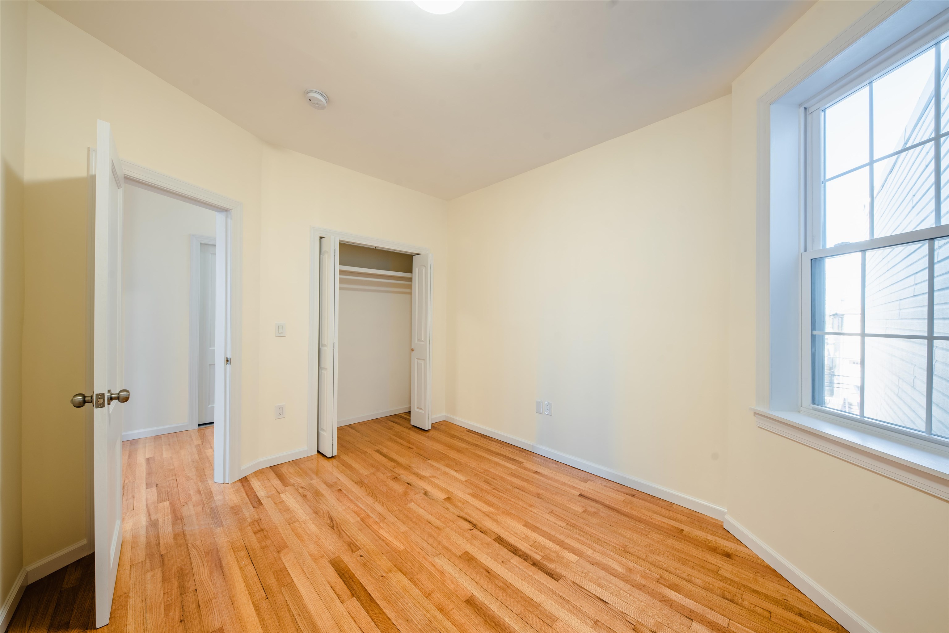 67 70th Street, Unit 2 Guttenberg, NJ 07093 - Photo 6 of 10 an empty room with wooden floor and a window