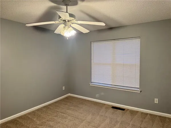 an empty room with a window and a fan