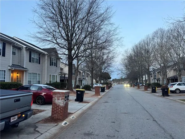 a view of road with card parked on side and retail shops