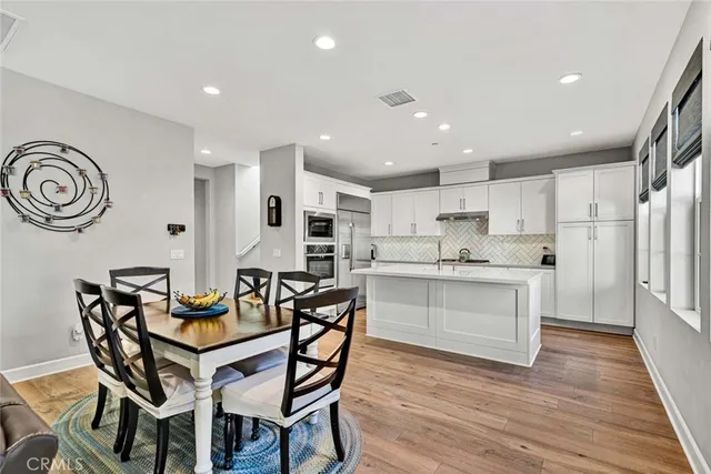 a kitchen with stainless steel appliances kitchen island granite countertop a wooden table chairs and white cabinets