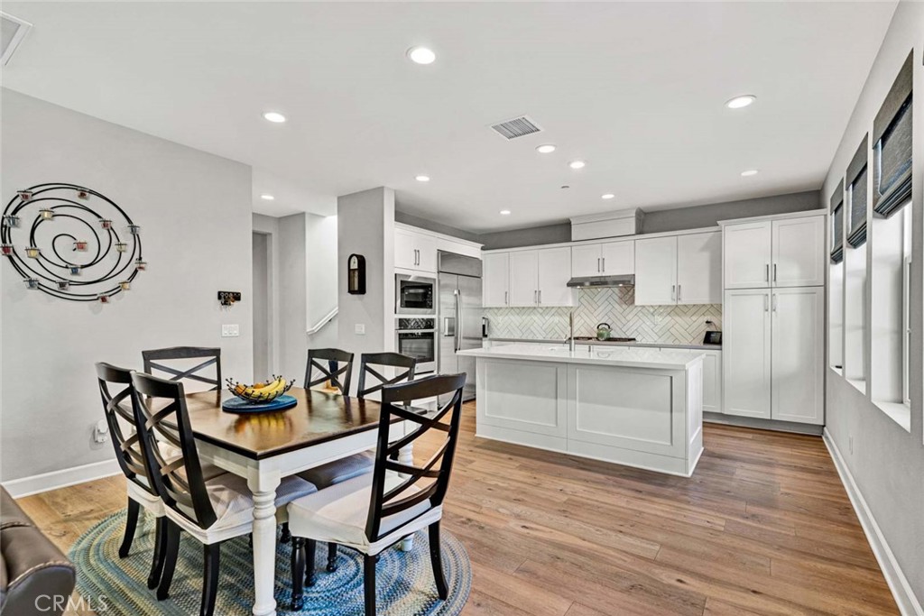 1270 Providence Loop Placentia, CA 92870 - Photo 12 of 59 a kitchen with stainless steel appliances kitchen island granite countertop a wooden table chairs and white cabinets