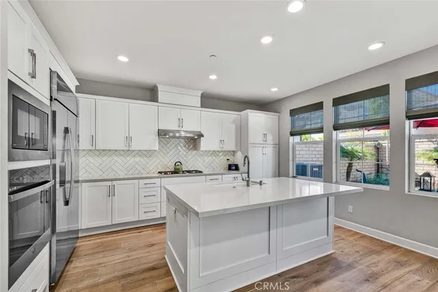 a large white kitchen with kitchen island a sink stainless steel appliances and cabinets