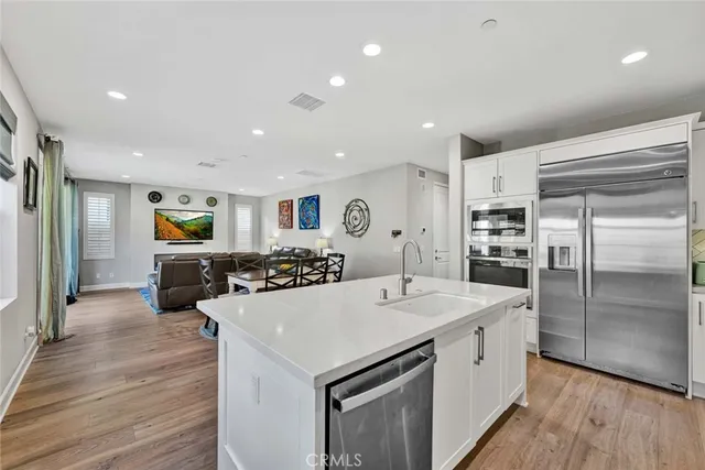 a large kitchen with sink a refrigerator and wooden floor