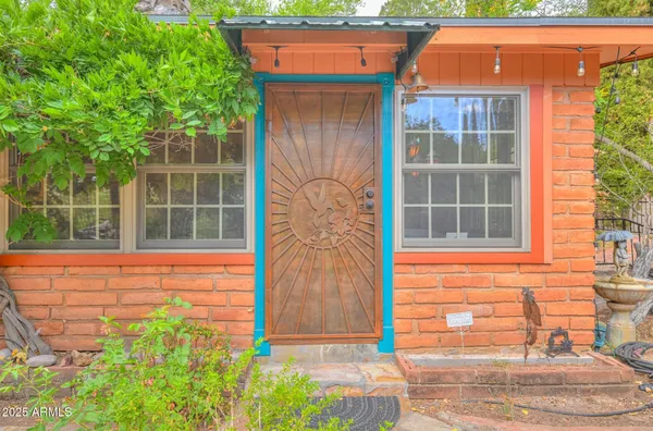 a view of a dining room with furniture a chandelier and large windows