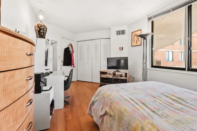 a bedroom with a bed a flat screen tv and a window