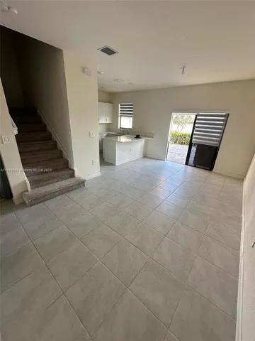 a view of kitchen and empty room with wooden floor