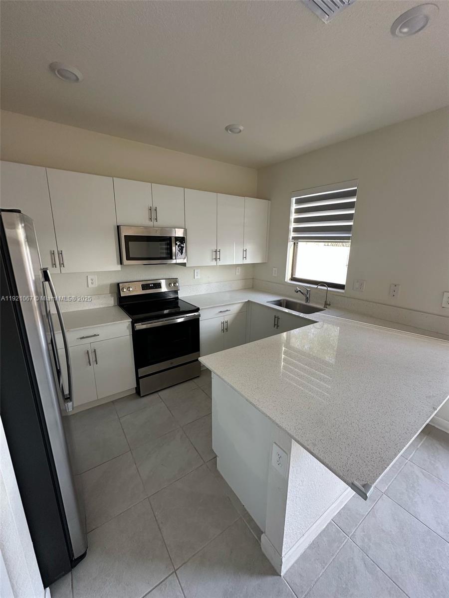 3302 West 114th Terrace Hialeah, FL 33018 - Photo 8 of 30 a kitchen with stainless steel appliances a refrigerator sink and microwave