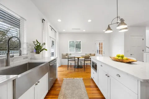 a kitchen with stainless steel appliances kitchen island a large counter top a stove a sink a dining table and chairs