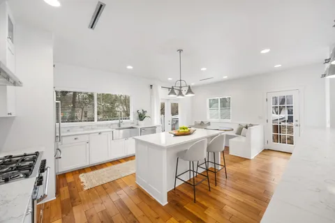 a view of a kitchen with a dining table chairs wooden floor and appliances