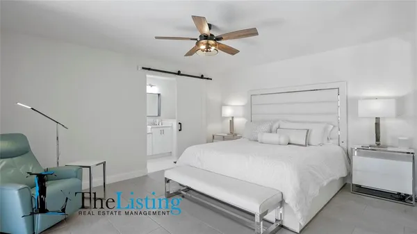a bedroom with a large bed and a chandelier fan