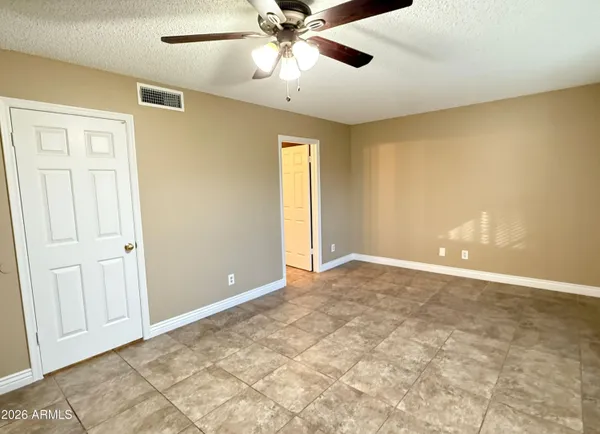 an empty room with windows and fan