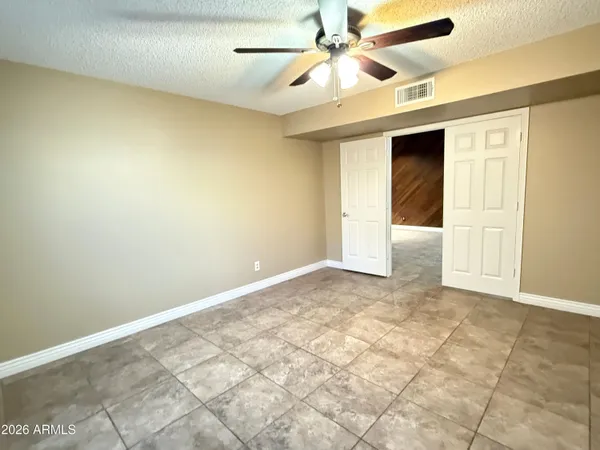 an empty room with a ceiling fan and carpet