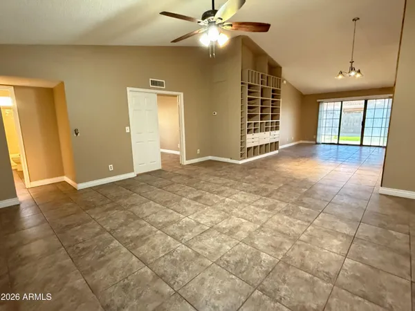 a view of an empty room with window and chandelier fan