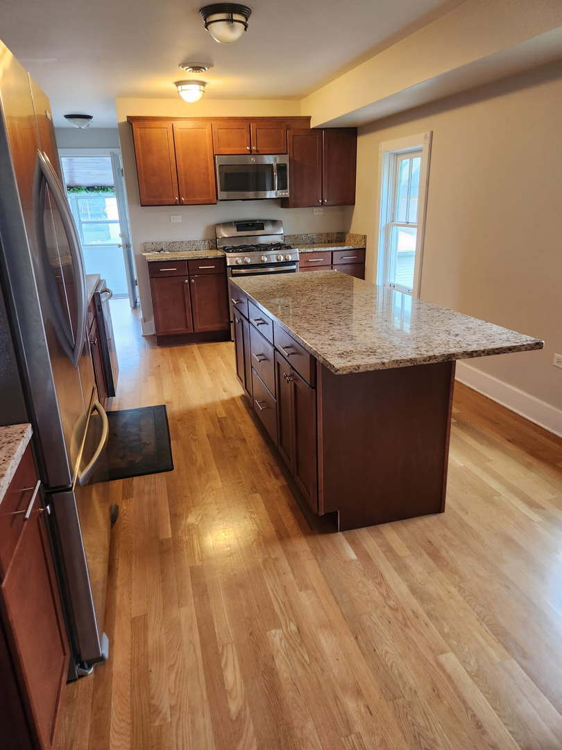 532 Beloit Avenue, Unit 2 Forest Park, IL 60130 - Photo 3 of 12 a large kitchen with stainless steel appliances granite countertop a stove a sink dishwasher a microwave oven and a refrigerator with wooden floor
