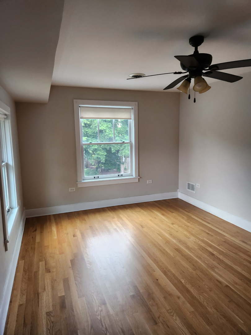 532 Beloit Avenue, Unit 2 Forest Park, IL 60130 - Photo 5 of 12 an empty room with wooden floor fan and windows