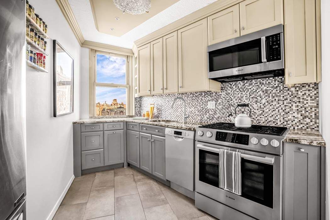 2025 Broadway, Unit 18D Manhattan, NY 10023 - Photo 3 of 12 a kitchen with stainless steel appliances granite countertop white cabinets a microwave a sink and a window