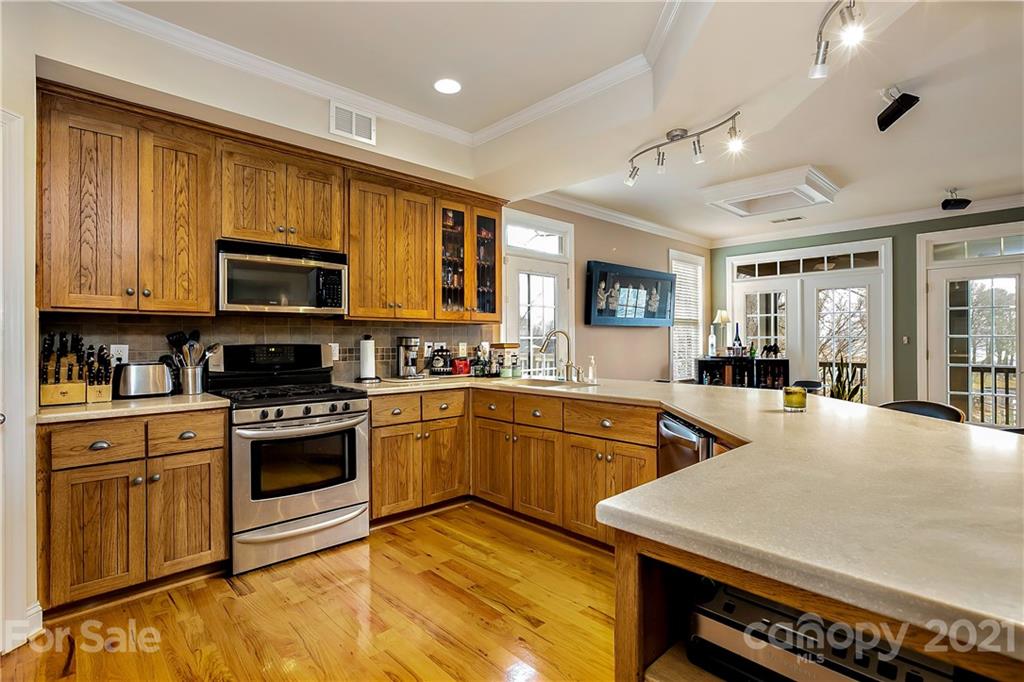 21036 Rio Oro Drive Cornelius, NC 28031 - Photo 17 of 29 a kitchen with stainless steel appliances granite countertop a stove top oven a sink dishwasher a dining table and chairs with wooden floor